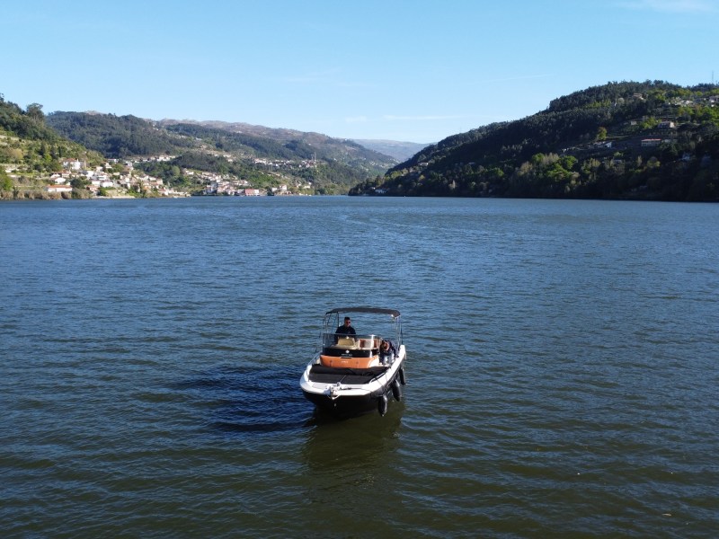 Boat on a lake with hills in the background under a clear blue sky.