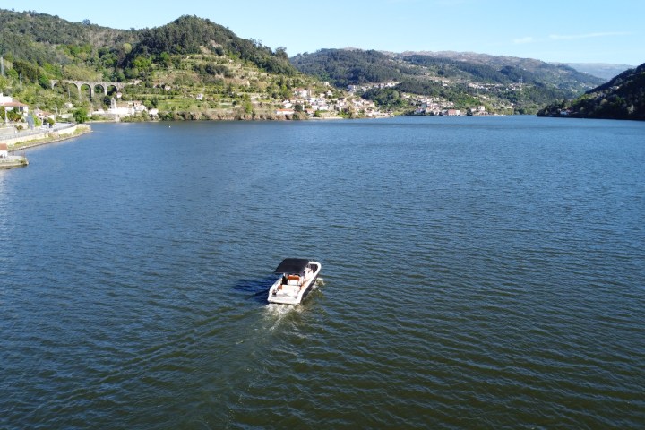 Boat on a large river with distant hills and scattered houses.