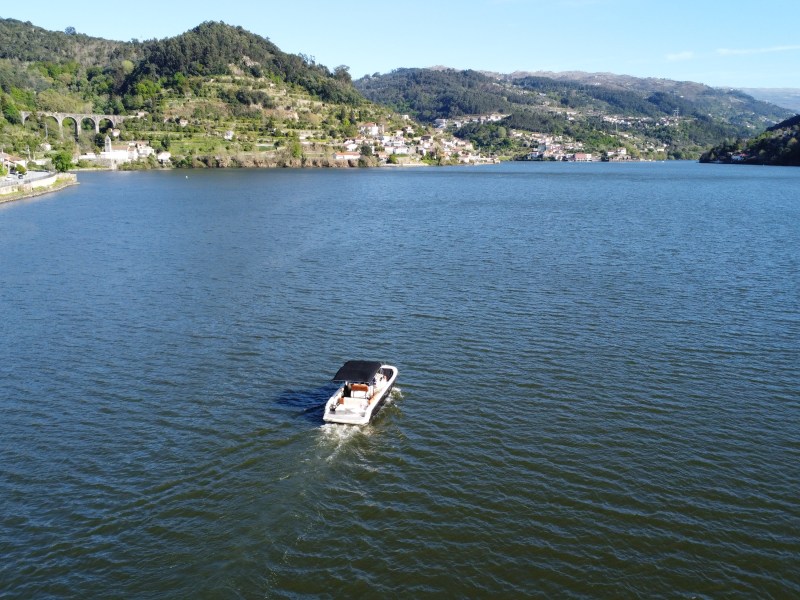 Boat on a large river with distant hills and scattered houses.