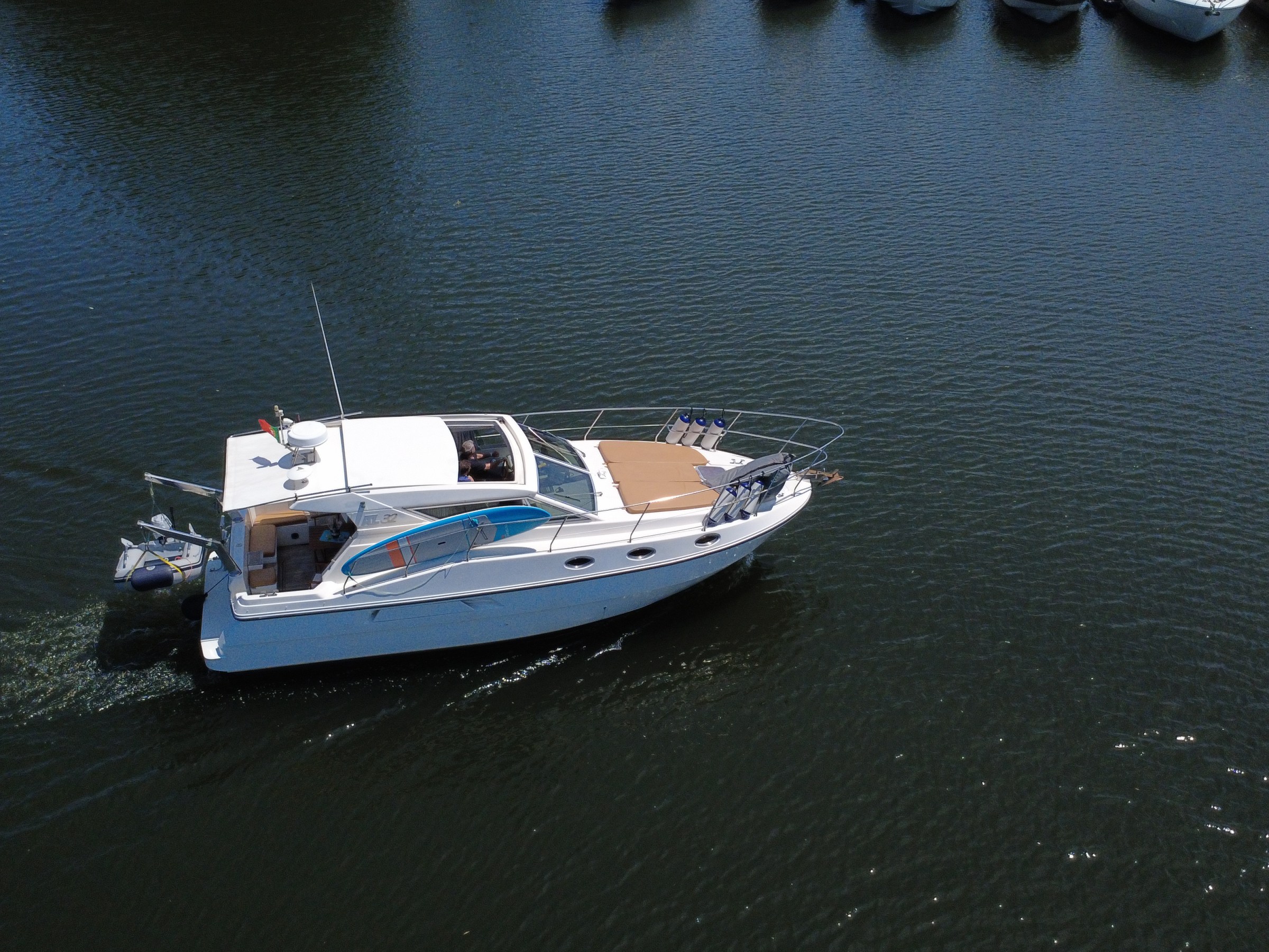 White motorboat cruising on calm water near a row of docked boats.