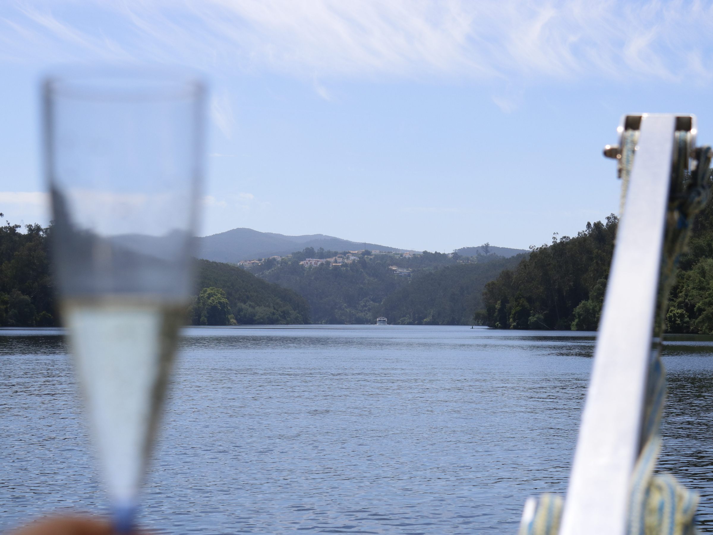 Champagne glass on boat with river and hills in background.