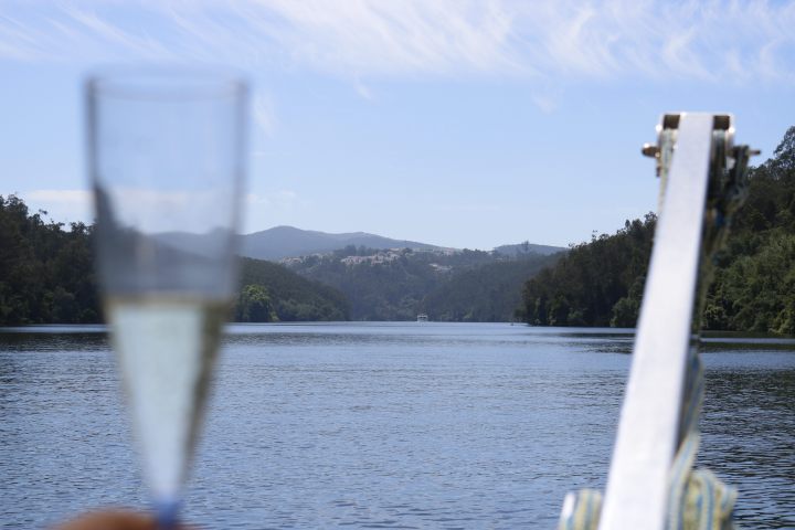 Champagne glass on boat with river and hills in background.