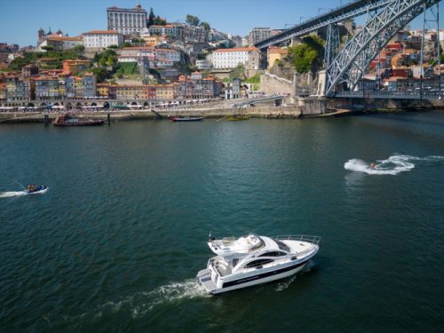 Boats on a river with a cityscape and large bridge in the background.