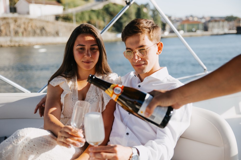 Couple on a boat having champagne poured into glasses.