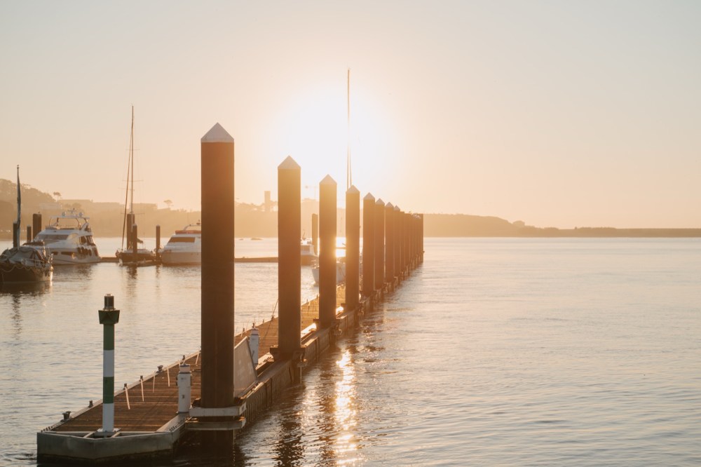 Wooden jetty over the river at sunset, with golden light reflected on the calm water