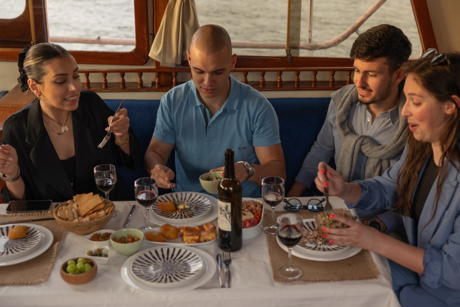 Four people enjoy a meal around a table on a boat.