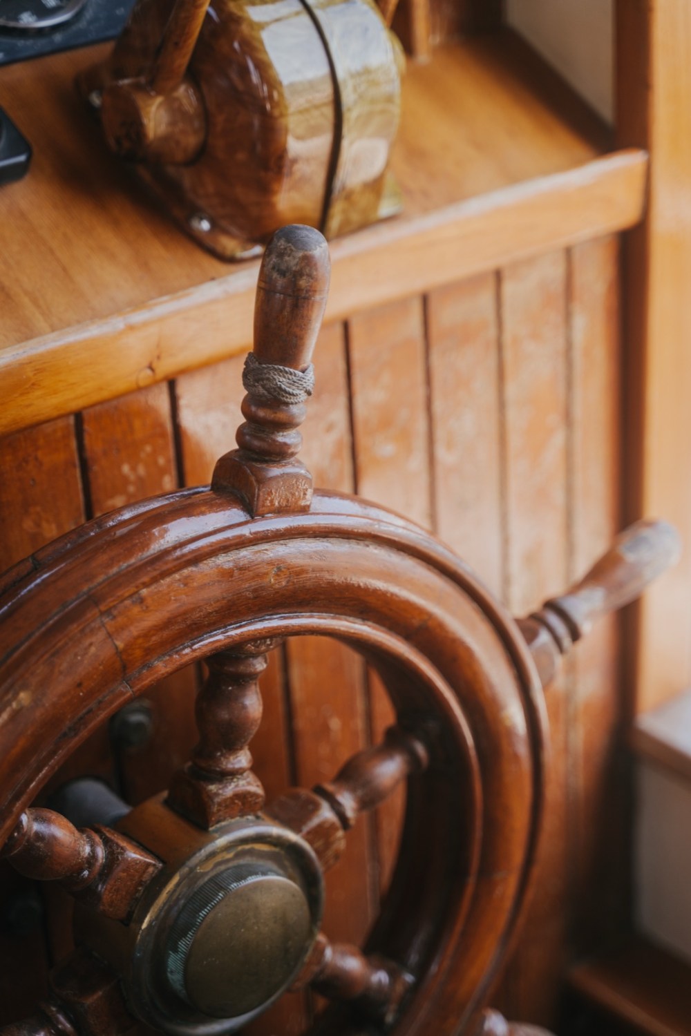 Wooden ship steering wheel with brass details on a wooden background.