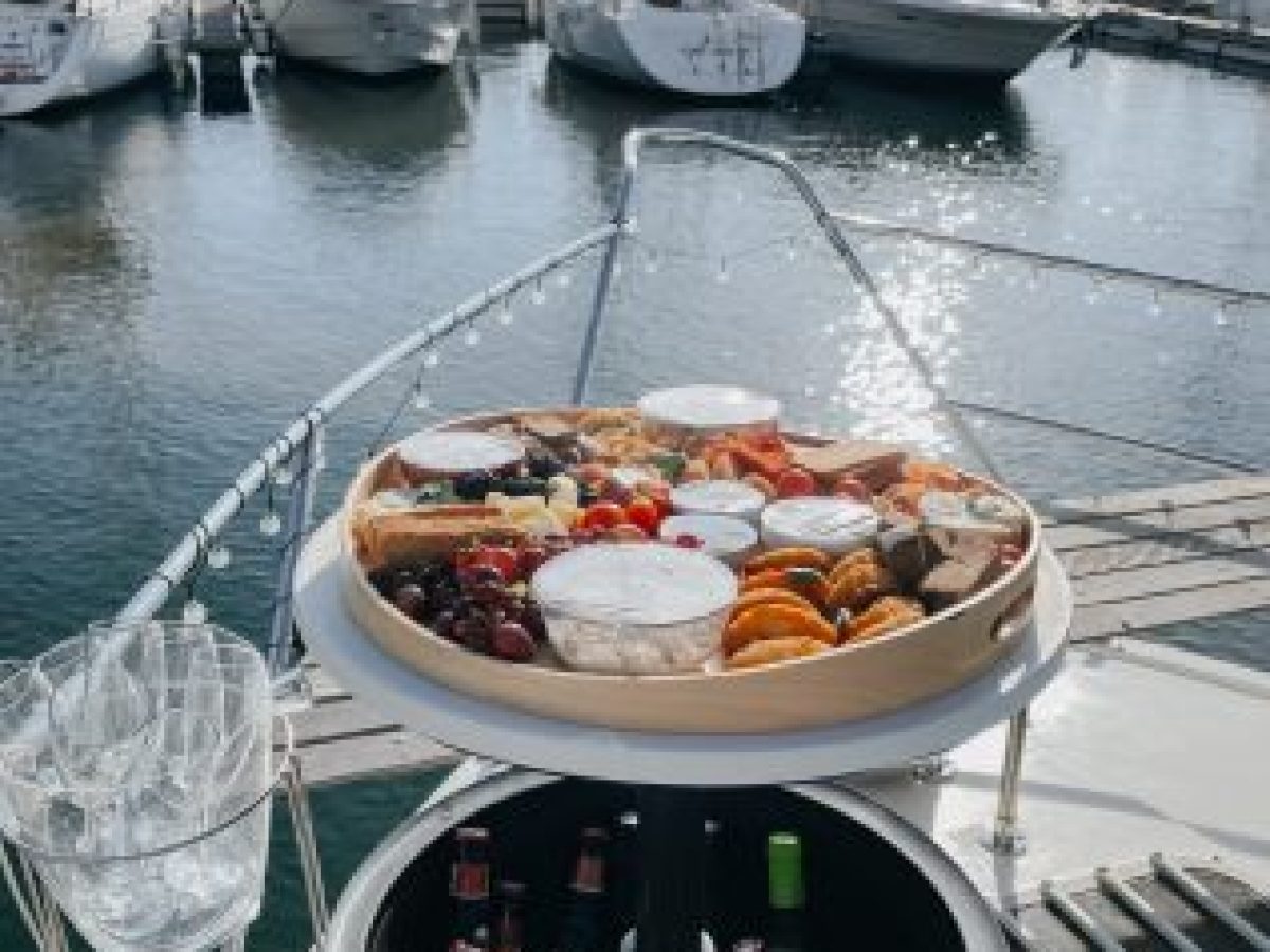 Tábua de queijos, enchidos, pão e frutos secos disposta no convés de madeira de um barco no Douro