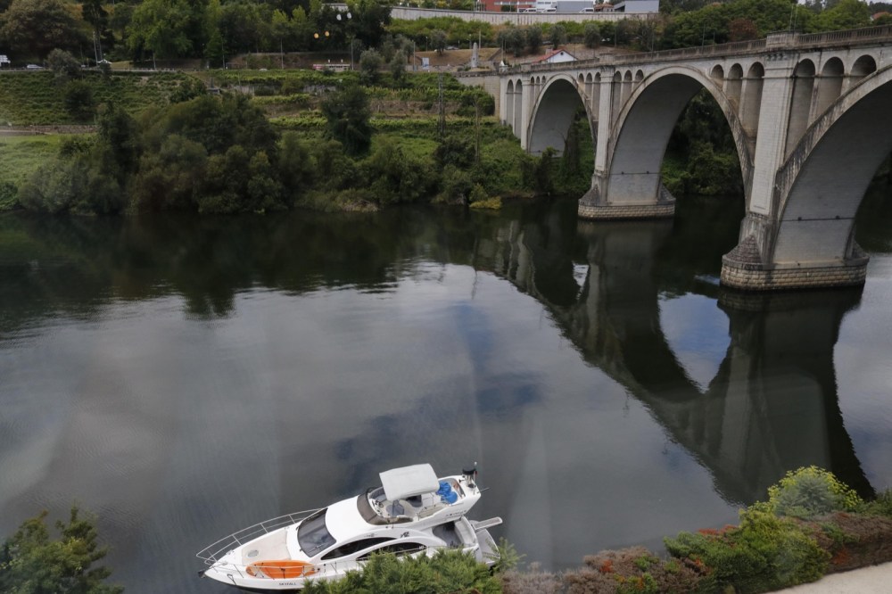Arched bridge over the Douro River with vineyard slopes in the background in the Alto Douro