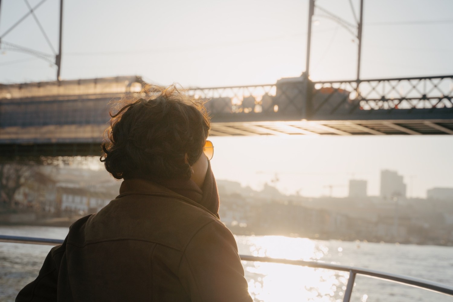 Passenger aboard watching the sun set behind the Luís I Bridge on the Douro River in late afternoon