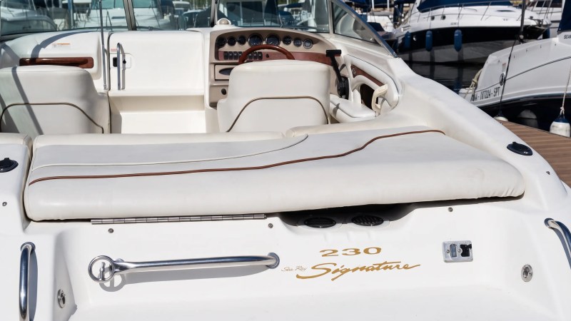 Interior of a white boat with leather seating and a wooden steering wheel.