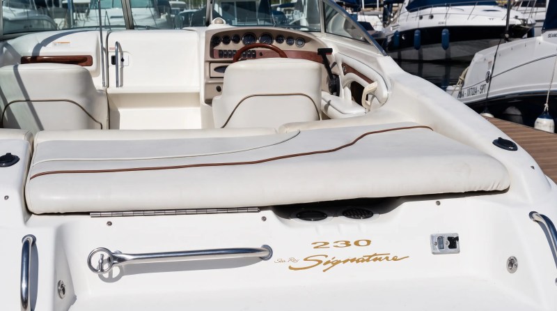 Interior of a white boat with leather seating and a wooden steering wheel.