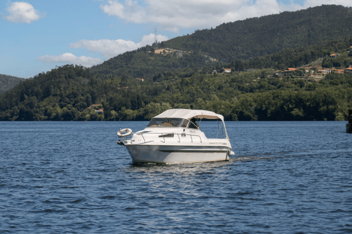 White motorboat on a lake with forested hills in the background.